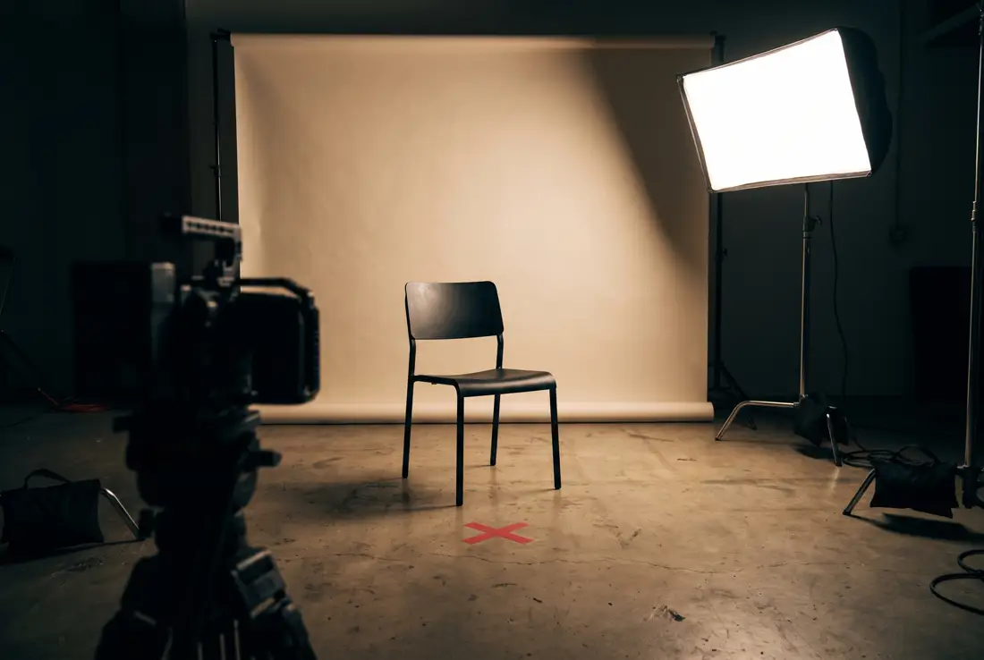 Film set: an empty chair, a softbox and a red tape mark on the floor